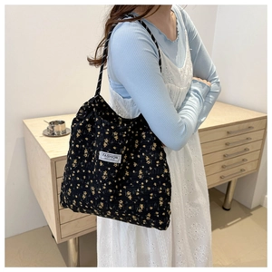 Detail of black floral nylon tote bag featuring yellow flower patterns and fashion label