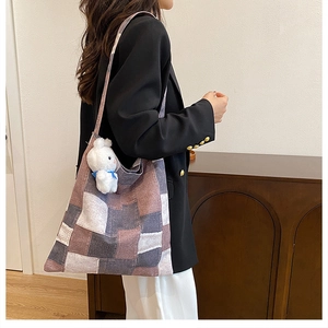 Dettaglio di una borsa tote in tela patchwork con ciondolo a coniglio e tracolla larga