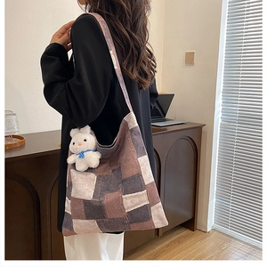 Détail du sac cabas en toile bicolore avec breloque lapin en peluche porté à l'épaule