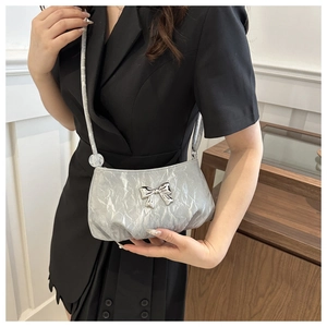Silver wrinkled crossbody bag with a metal bow decoration and thin shoulder strap