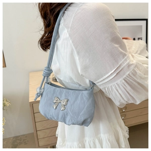 Detail of light blue pleated shoulder bag with silver bow and transparent beads