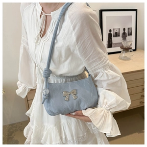 Detail view of light blue pleated shoulder bag with silver bow and crystal ball pendant