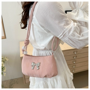 Close-up of pink crossbody bag with silver bow charm and transparent bead strap detail