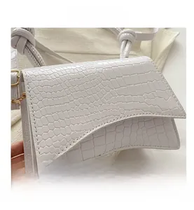Detailed view of white crocodile pattern texture and knot detail on small crossbody bag