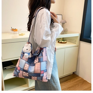 Détail du sac seau en toile avec design patchwork et pendentif lapin en peluche blanc