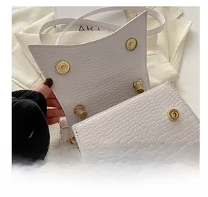 Detail view of white crocodile pattern bag featuring secure dual gold magnetic buckles