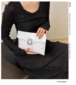 Detail of white crocodile pattern envelope clutch with a luxury crystal buckle