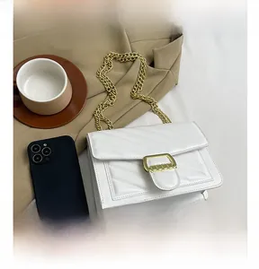 Close-up of white quilted crossbody bag with gold metal buckle and chain strap
