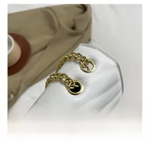Detail of white quilted crossbody bag showing gold metal eyelets and chain strap quality