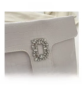 Macro view of white crocodile embossed clutch bag with a luxury crystal buckle
