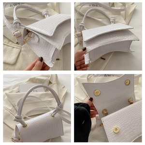 Detail of white crocodile pattern bag with curved base, gold buckle and knotted handle