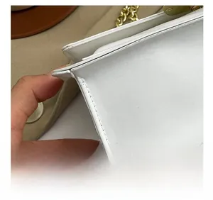 Macro shot of precise stitching and gold chain on this white quilted crossbody bag