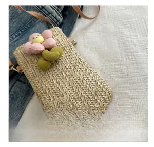Detail of woven straw mini phone bag with 3D floral decoration on denim background