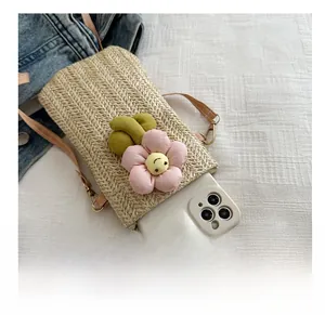 Detail show of woven straw phone bag with pink fabric flower and brown strap