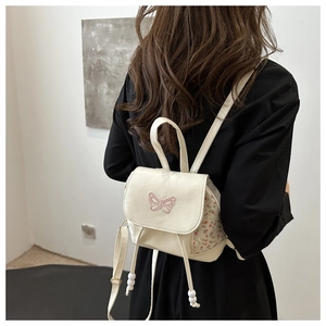 Detail of cream backpack with pink butterfly embroidery and floral fabric patchwork