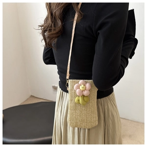 Detail of hand-woven straw crossbody bag featuring a plush 3D sunflower and slim strap