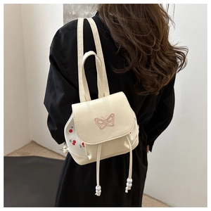 Detail of floral butterfly embroidery and cherry print on white mini bucket backpack