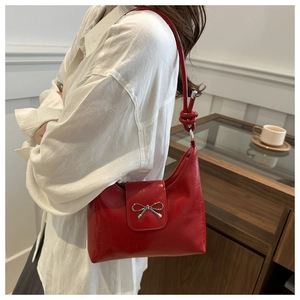 Vue détaillée d'un sac rouge brillant avec nœud argenté et bandoulière à nœud manuel