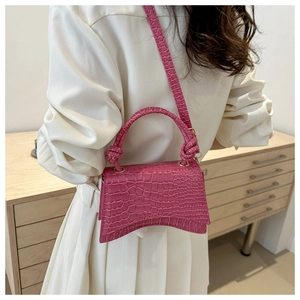 Detail of rose red hourglass bag featuring crocodile pattern and knotted handle