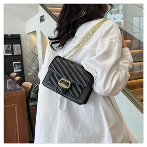 Model view of black quilted crossbody bag with gold chain strap and metal clasp detail
