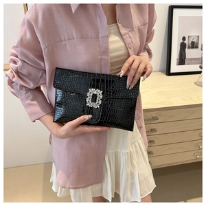 Detail of black crocodile-embossed envelope clutch featuring a luxury crystal square buckle