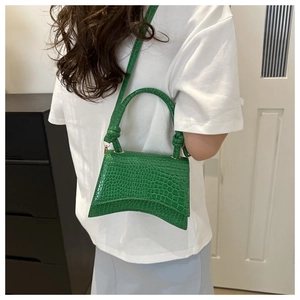 Detail of emerald green crocodile pattern handbag with classic curved hourglass bottom