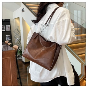 Detail of dark brown tote bag with square stitching pattern and silver chain strap accent