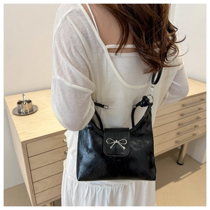 Detail of black pleated faux leather bag featuring a silver metal bow buckle accent