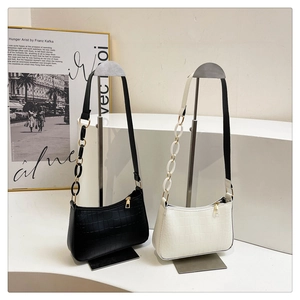 Detail of minimalist crocodile pattern underarm bags in black and cream with gold zipper