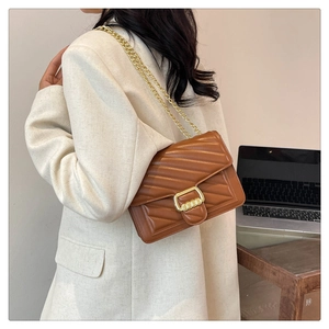 Brown quilted crossbody bag with gold chain strap shown in a professional office setting