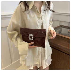Detail of a dark brown crocodile pattern PU leather clutch bag with a crystal buckle