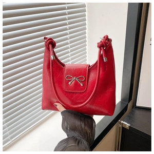 Close-up of a red cracked leather bucket bag with a silver metal bow buckle detail