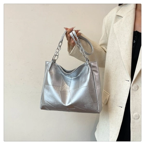 Detail of silver metallic tote bag featuring geometric patchwork design and chain handle