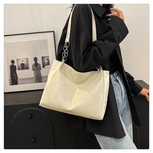 Detail of off-white tote bag with geometric stitching and elegant metal chain strap