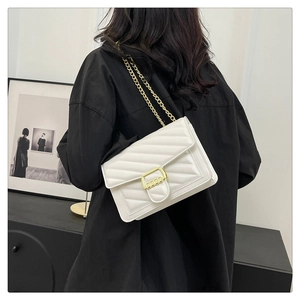 Detail of white quilted flap bag with golden chain strap and rectangular metal buckle