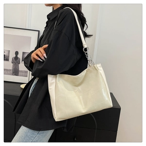 Close-up of white tote bag with geometric texture and silver chain strap detail