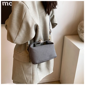 Detailed view of the textured grey shoulder bag with elegant gold hardware on a model