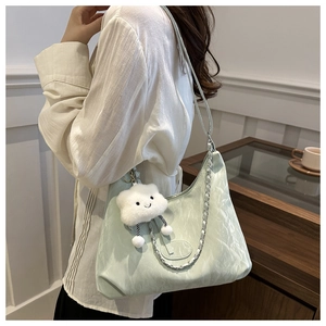 Model view of a light green pleated hobo bag with silver chain and plush cloud charm