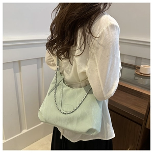 Dettaglio della borsa tote verde menta con trama a pieghe e catena d'argento elegante