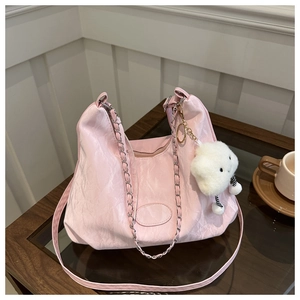 Detailed texture of pink pleated shoulder bag with silver chain and white cloud charm