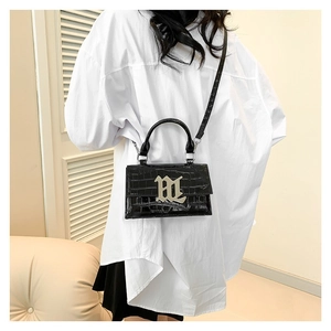 Chic black crocodile embossed mini square bag with silver metal M logo shown on a model
