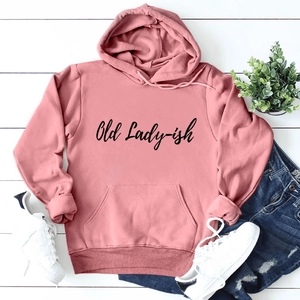 Flat lay of pink 'Old Lady-ish' hoodie with blue jeans and sneakers on white wood