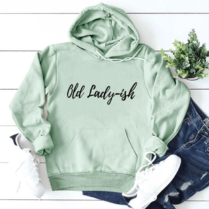 Flat lay of a mint green hoodie with Old Lady-ish text, jeans, and white sneakers
