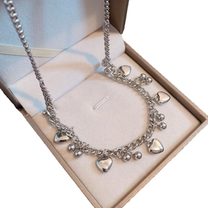 Collier à grosse chaîne argentée avec breloques cœur et perles dans un écrin à bijoux