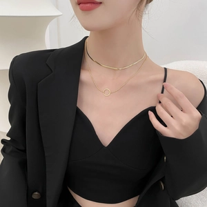 Collana minimalista a doppio strato in titanio dorato con ciondolo rotondo su modella elegante