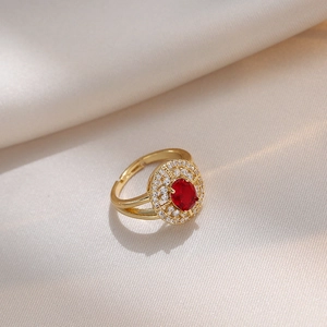 Bague en acier titane doré avec pierre rouge ovale et zircons sur fond de satin