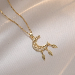 Gold moon dreamcatcher necklace with white zircon and feather charms on fabric
