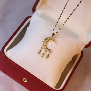 Detail of gold moon dreamcatcher necklace with leaf charms in a velvet gift box