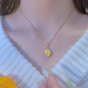Unique durian pendant necklace in gold finish worn on a white sweater background