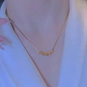 Collana minimalista in acciaio al titanio dorato con cinque perle sfaccettate su modella